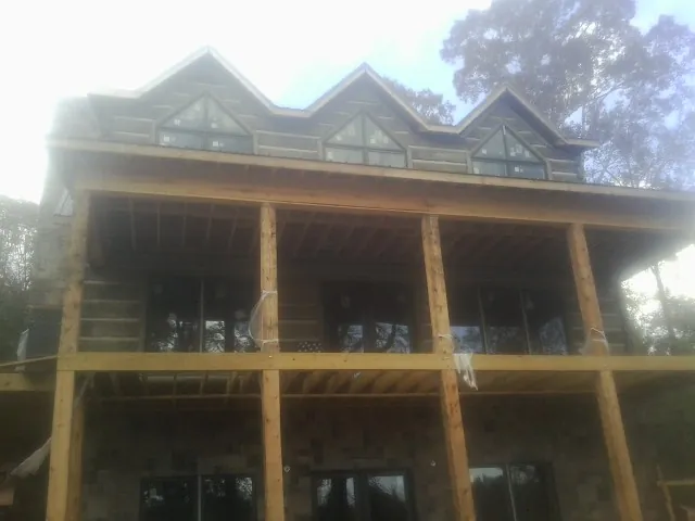 Dormers and porch framing on a large log home under construction — Roof Coating work by our crew in El Dorado Springs