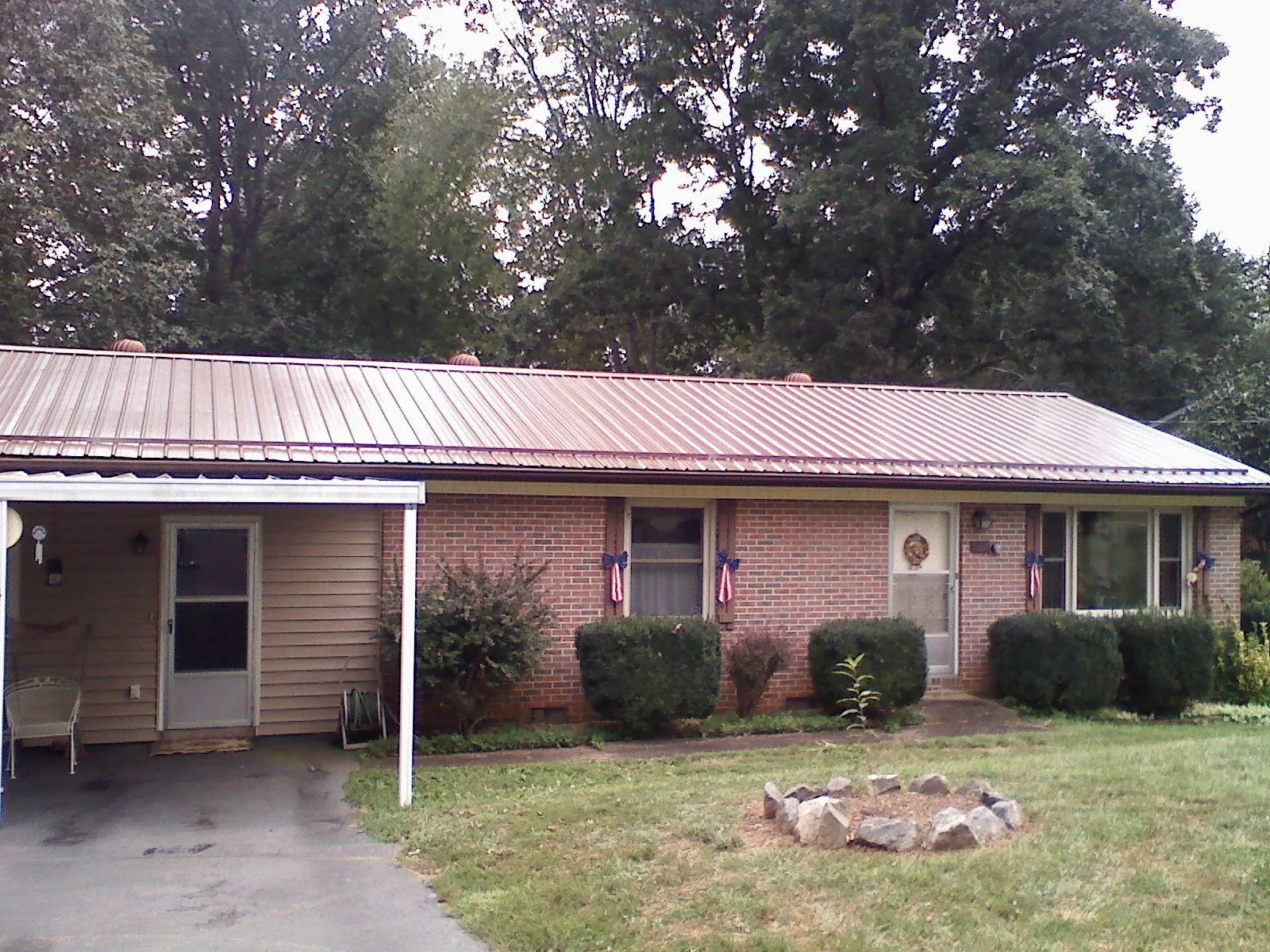 Bronze metal roof and carport on a brick ranch home — Roof Repair work by our crew in El Dorado Springs