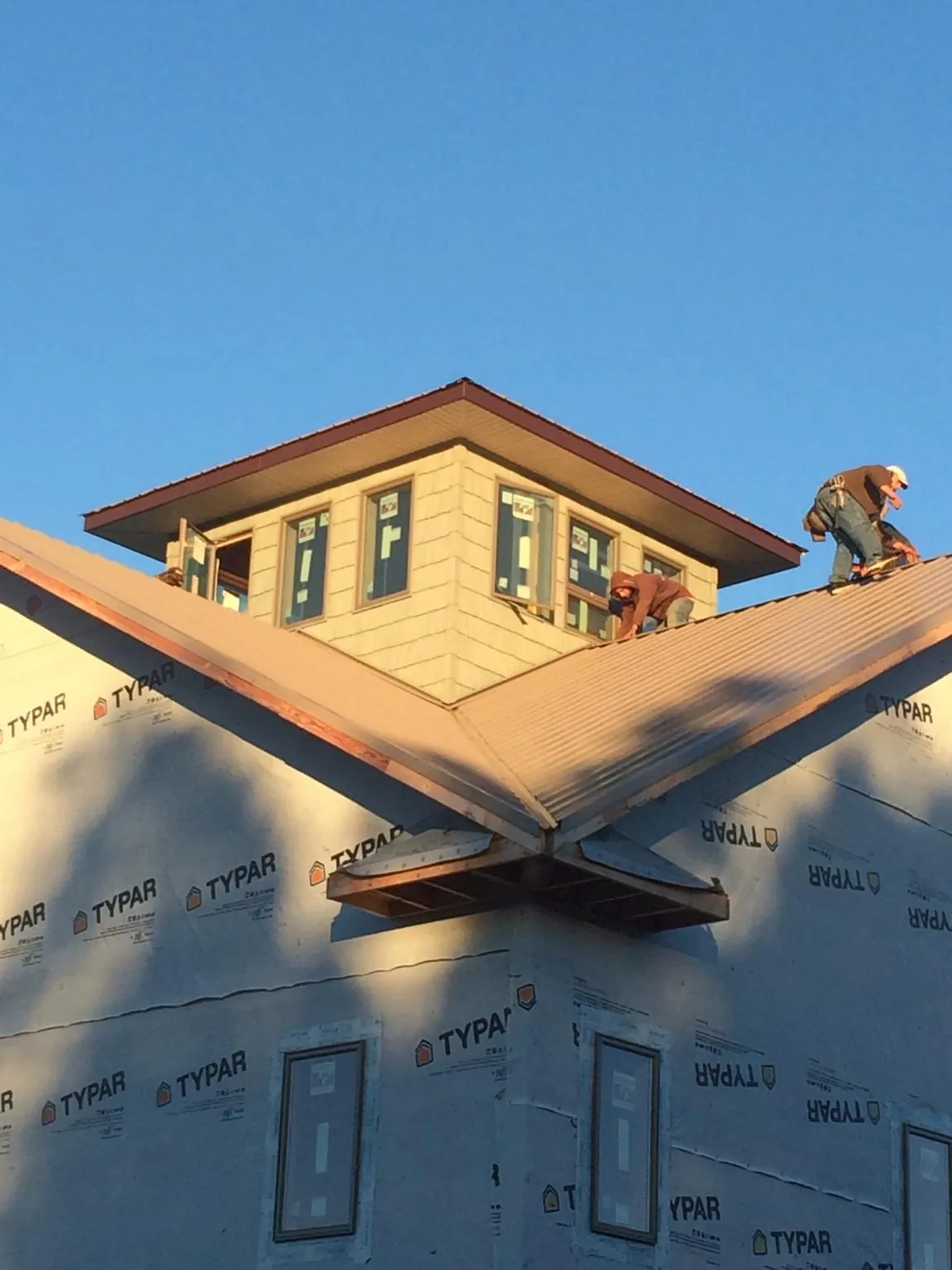 Roofers working around a rooftop cupola on a new metal roof at sunset — Roof Waterproofing in El Dorado Springs by Roofing Brothers